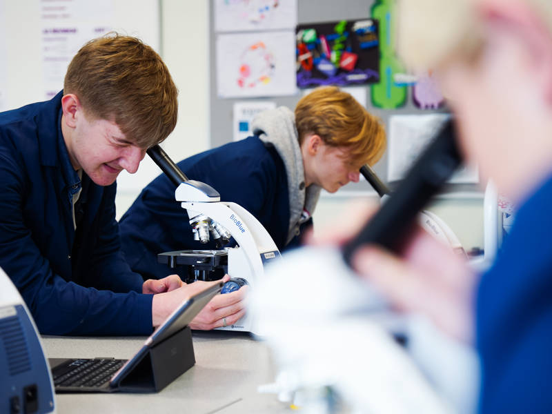 Science student looks through microscope in science laboratory