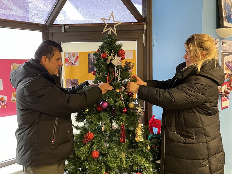 Male and female students decorating Christmas tree.