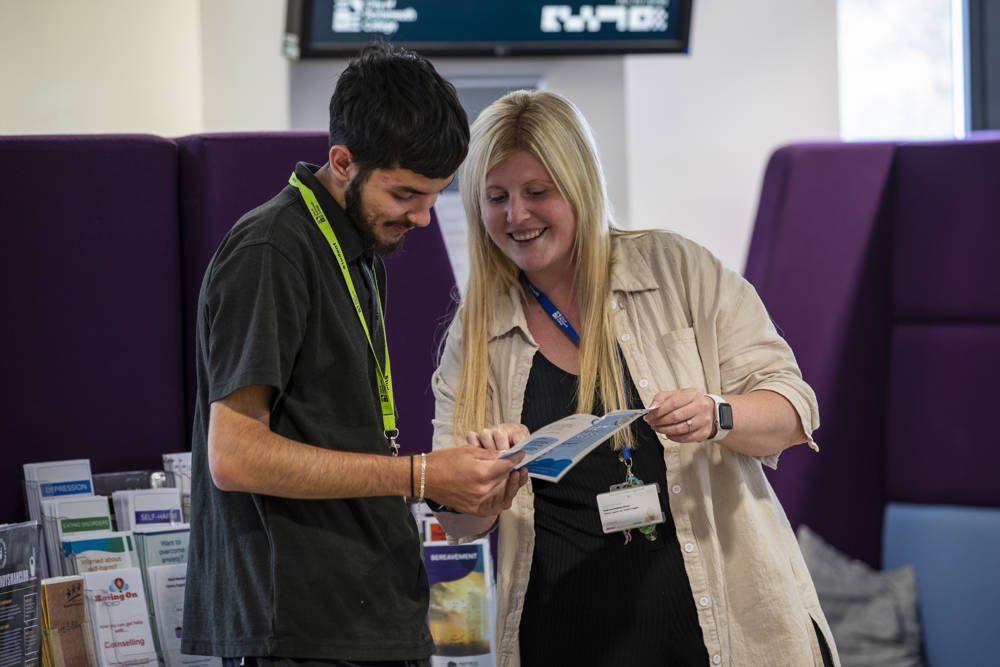 Student being shown guidance leaflet by student support staff member.