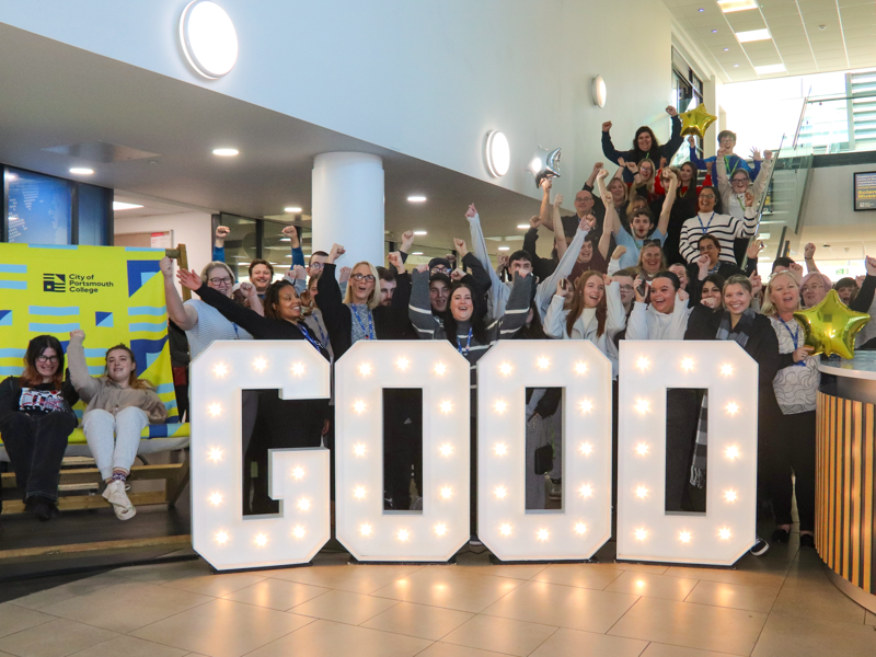 Students and staff at City of Portsmouth Colleges' Highbury Campus surrounding good in light up letters