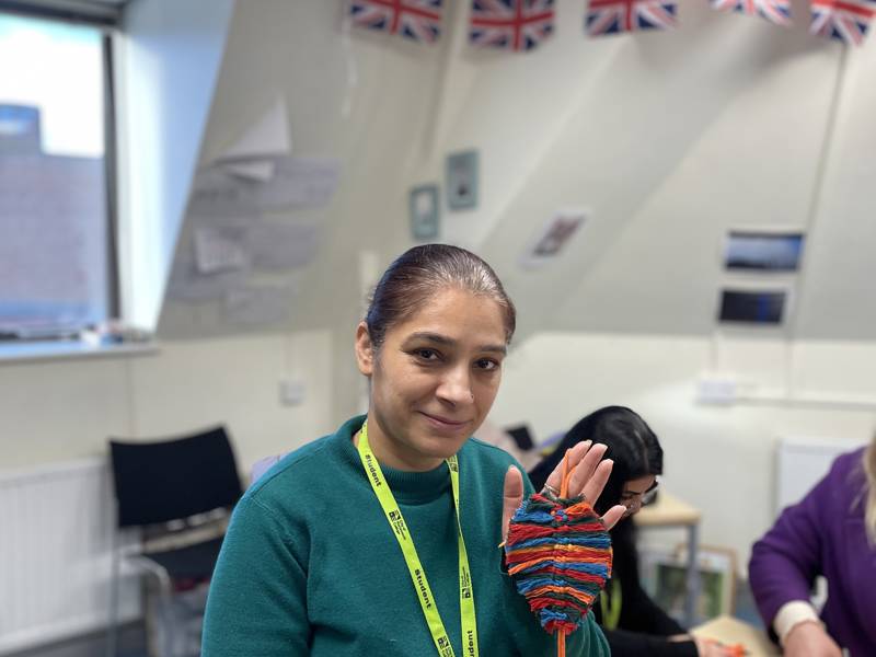 Female ESOL student showing off her macrame skills.