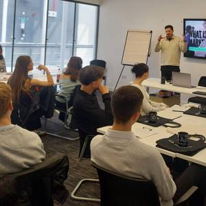 Marketing students in a classroom watching a presentation by a representative of Astute People