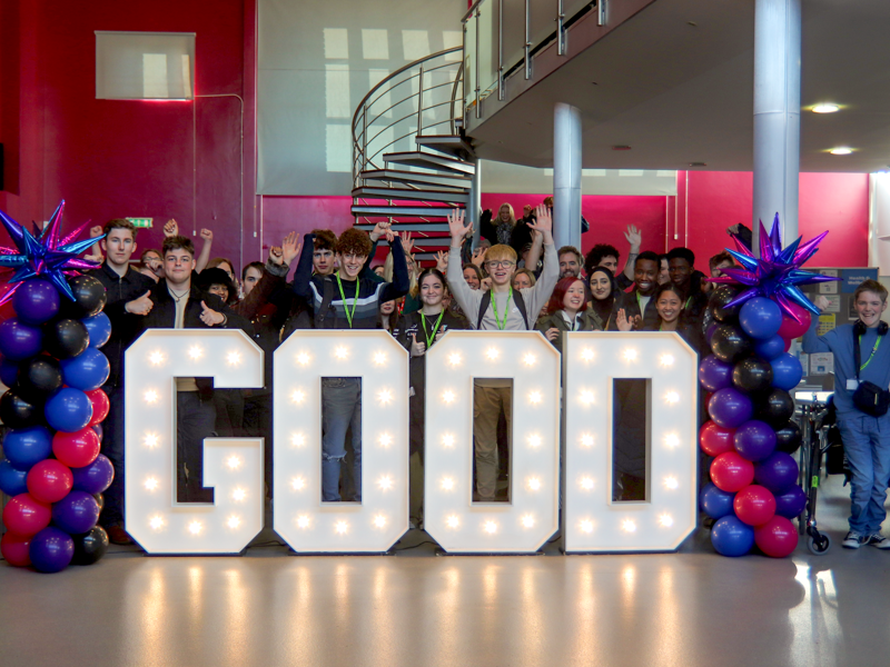 Students and staff at City of Portsmouth Colleges' Sixth Form Campus surrounding good in light up letters