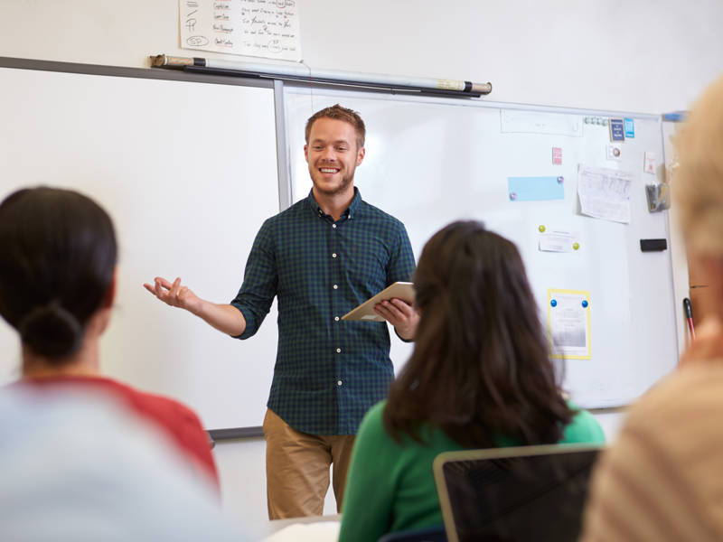 Male teacher listening to students at adult education class