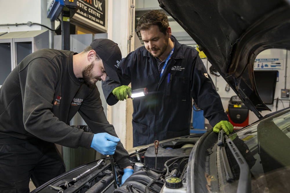 An automotive student working on a car at City of Portsmouth College
