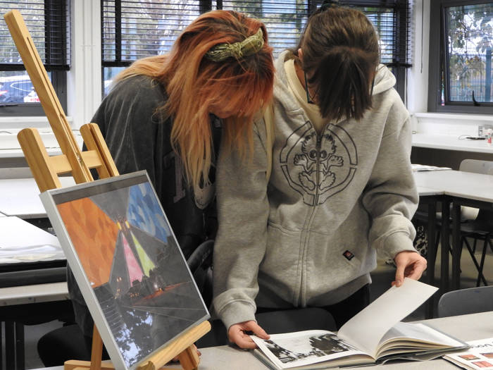 Two girls look through a picture book