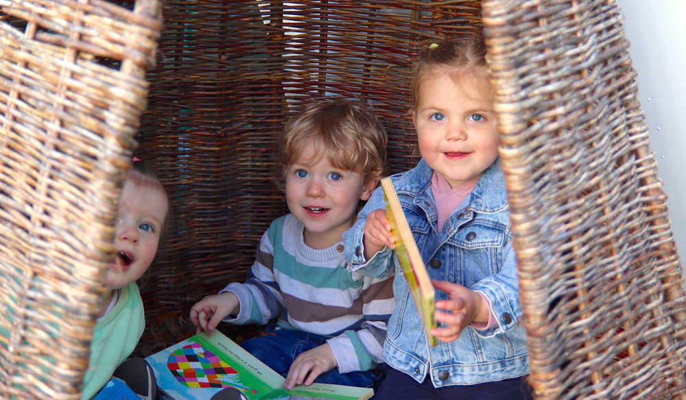 Children playing happily in a wicker teepee at Honeypot Nursery, City of Portsmouth College.