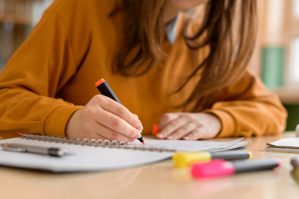 A female studying revising with paper books and a highlighter 