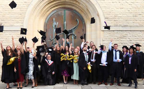 City of Portsmouth College's 2025 adult learner graduates throw their hats into the air outside Portsmouth Cathedral