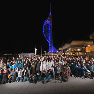 A group of people cheering in front of Portsmouth's Spinnaker Tower